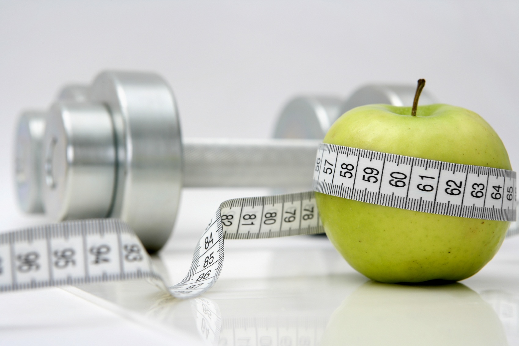 A picture of measuring tape, an apple, and a pair of dumbbells