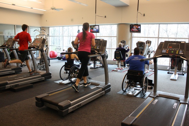 5 individuals are utilizing multiple cardio machines in a fitness center