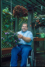 Wheelchair user tending plants in low hanging baskets