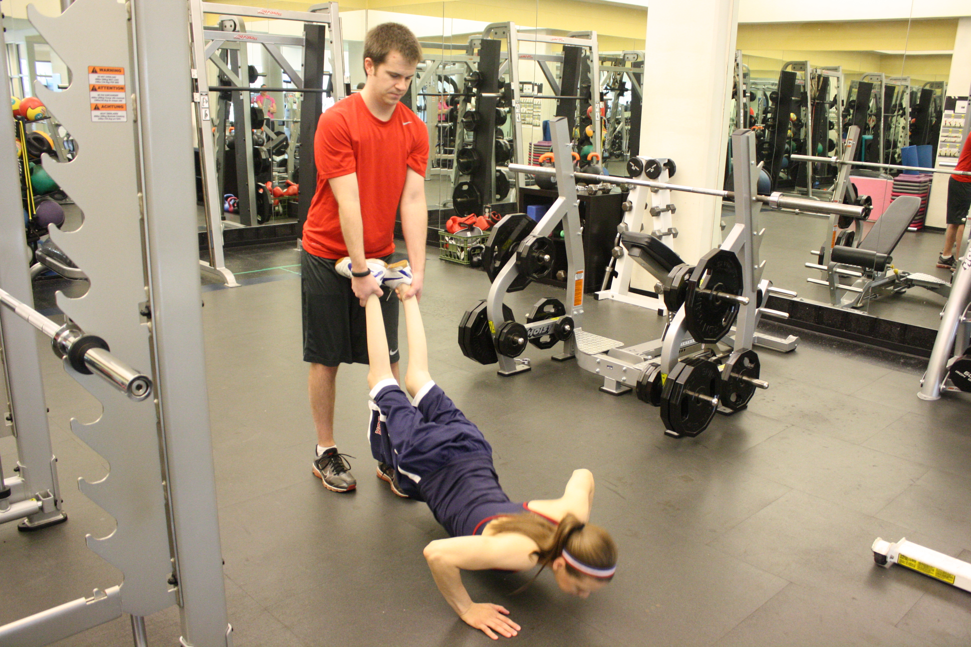 trainer assists client with pushups