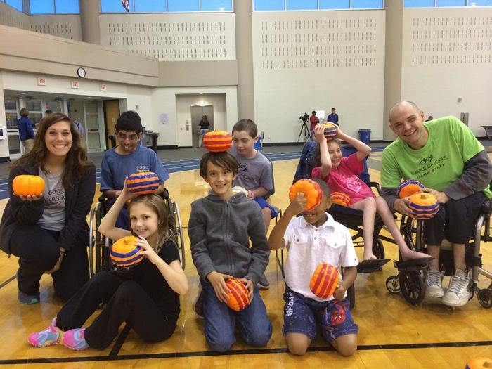 a group of children and staff hold pumpkins for bocce