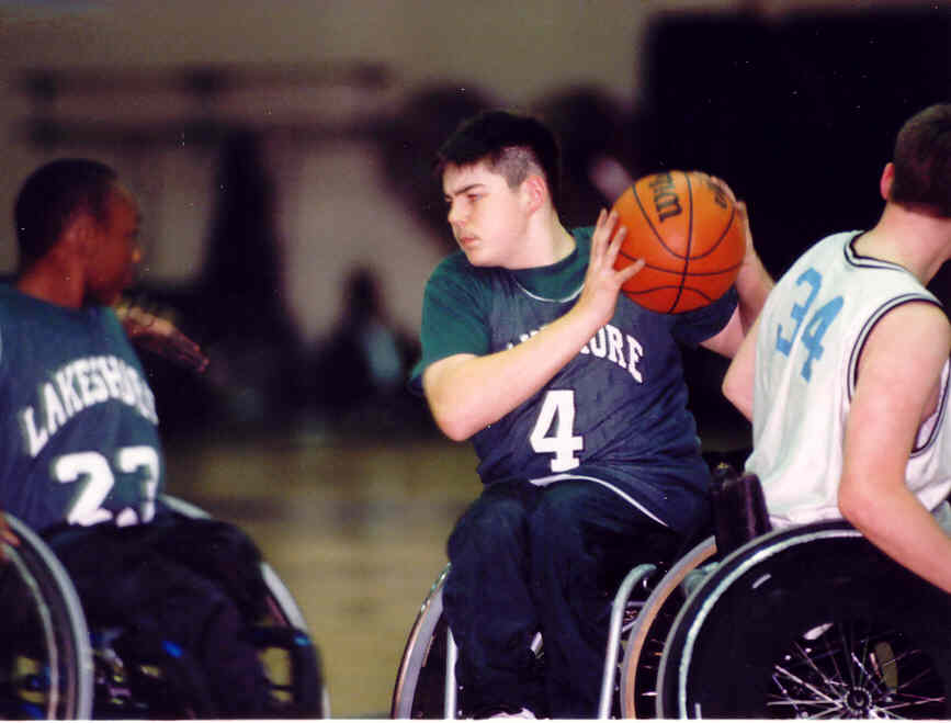 three young men play wheelchair basketball