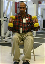 A man is seated demonstrating the end position for a Hammer Bicep Curl with Free Weights exercise
