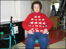 A woman seated in a wheelchair is demonstrating the start position for a Upright Row with Free Weights exercise