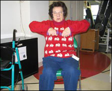A woman seated in a wheelchair is demonstrating the end position for a Upright Row with Free Weights exercise