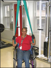 A woman is seated demonstrating an end position for a Lat Pull Down with Thera-Band® exercise