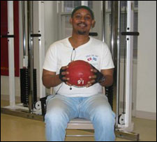 A man is seated demonstrating a start position for a Trunk Rotation Exercises with a Medicine Ball