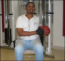 A man is seated demonstrating an end position for a Trunk Rotation Exercises with a Medicine Ball