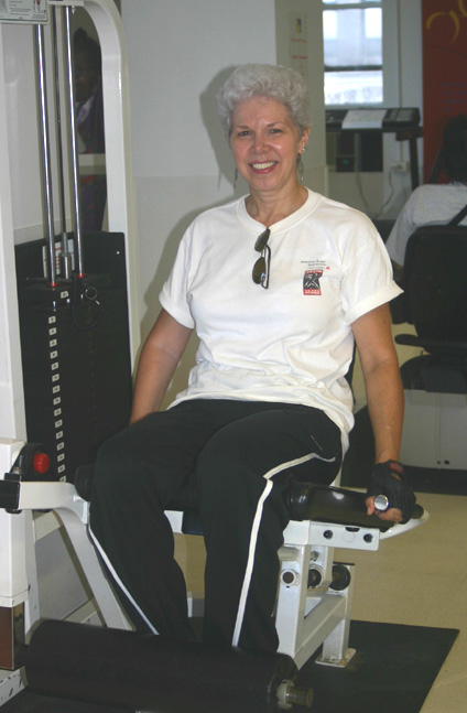 An adult woman is sitting on a Leg Extension exercise equipment