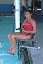 A life guard demonstrates the operation of a pool lift.     