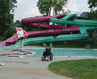 A wheelchair sits in front of a water slide at an aquatic facility.