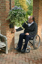 Older man using wheelchair tending a 24-inch hanging planter