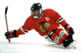 Sledge ice hockey player on ice in red uniform holding hockey stick