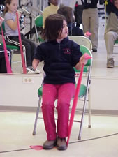 Child with an upper extremity amputation is  exercising with an elastic resitance band.