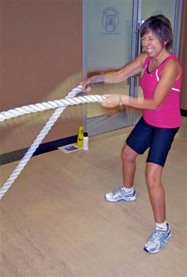 A woman is pulling at two large ropes while grimacing. 