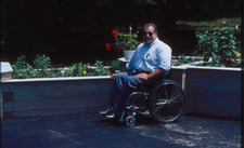 Wheelchair user seated near wooden raised planter beds