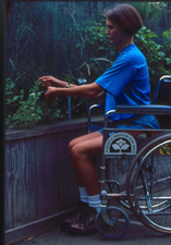 Young woman using a wheelchair without footrests tending herbs in a 24 inch high and wide raised bed made from untreated cedar.