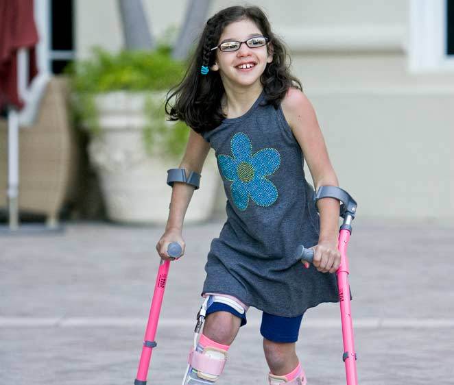 A girl walks using assistive poles