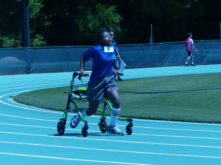 a girl uses an assistive walker to participate in a track event