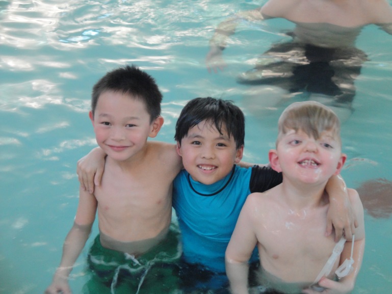 3 kids stand in a pool