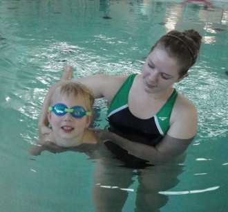 a woman holds a child as he practices swimming
