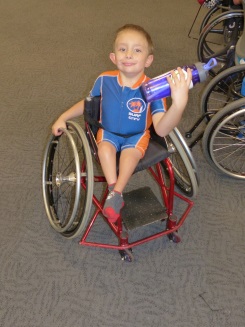 a boy in a wheelchair holds a water bottle