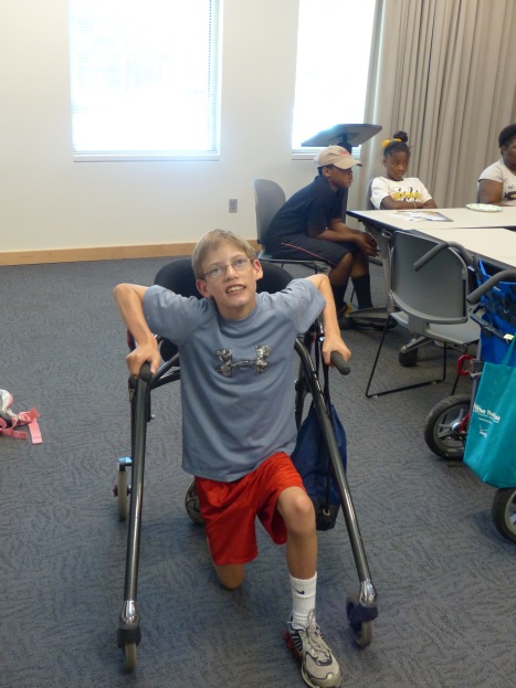 a boy does lunges with the aid of a walker device