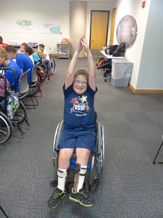 a boy in a wheelchair does the arm jacks exercise