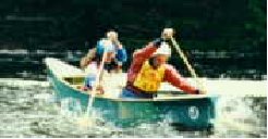 Two people are paddling in an open canoe.