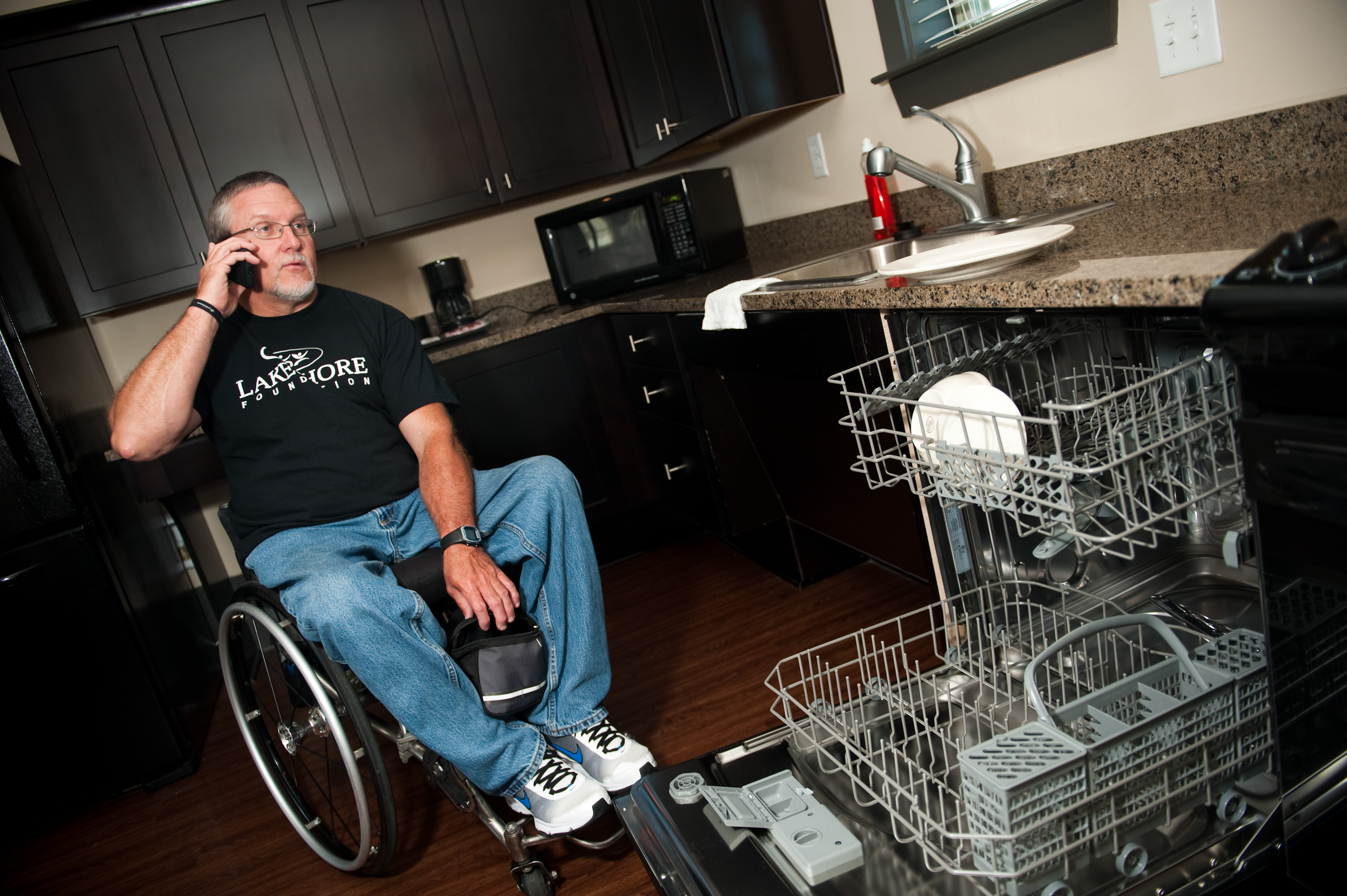 man in wheelchair speaks on cell phone while in kitchen