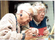 Two older women are painting.