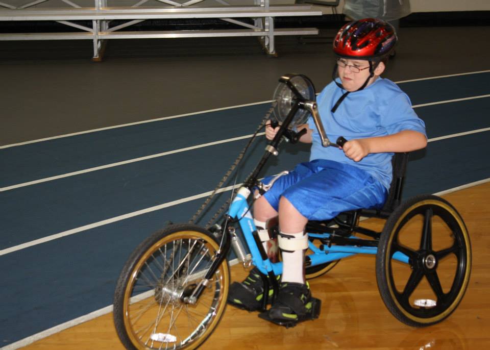 boy riding handcycle with helmet on