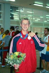 A young athlete holding up his medal.