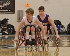 2 boys pushing on a wheelchair basketball court