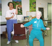 Two older women are exercising using an elastic resistance band.