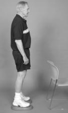 A man is standing next to a chair demonstrating standing on foam