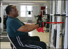 A man is seated demonstrating a start position for a Seated Row with Thera-Band® exercise
