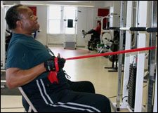 A man is seated demonstrating an end position for a Seated Row with Thera-Band® exercise