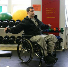 A man is seated demonstrating a start position for a Chest Fly with Thera-Band® exercise