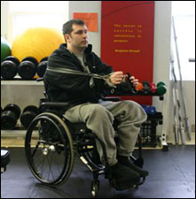 A man is seated demonstrating an end position for a Chest Fly with Thera-Band® exercise