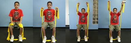 Child with Spina Bifida is performing an Overhead Reach exercise from a seated position.
