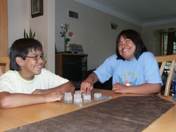 A girl with Down Syndrome and her brother play a game of tic, tac, toe.