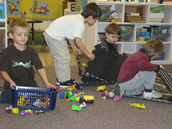 Four young friends with and without disabilities work together to clean up toys