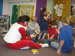 Image of several children practicing on their musical instruments with two adults.