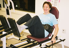 A woman smiles at the camera while seated on an exercise machine.