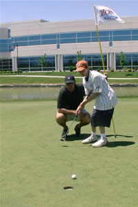 A man watches a pre-teen boy sink a shot on a golf course.