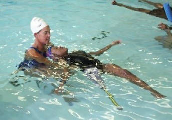 Adapted Aquatics instructor is providing instruction to participant in pool where the participant is in a back floatation position.