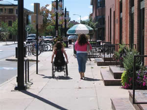 A woman walking with a woman using a manual wheelchair