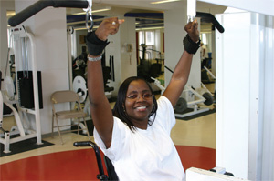 A woman uses the lat pull down machine with wrist cuffs