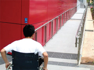 Image of a man in a wheelchair pushing up a long ramp